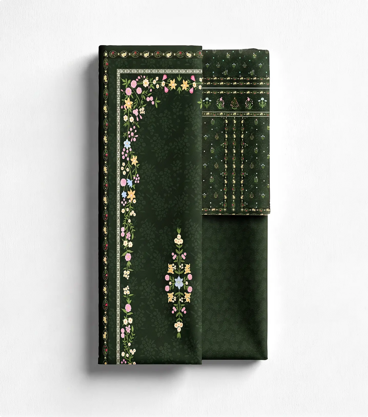 Unstitched forest green lawn shirt panel with floral border print beside matching trouser fabric