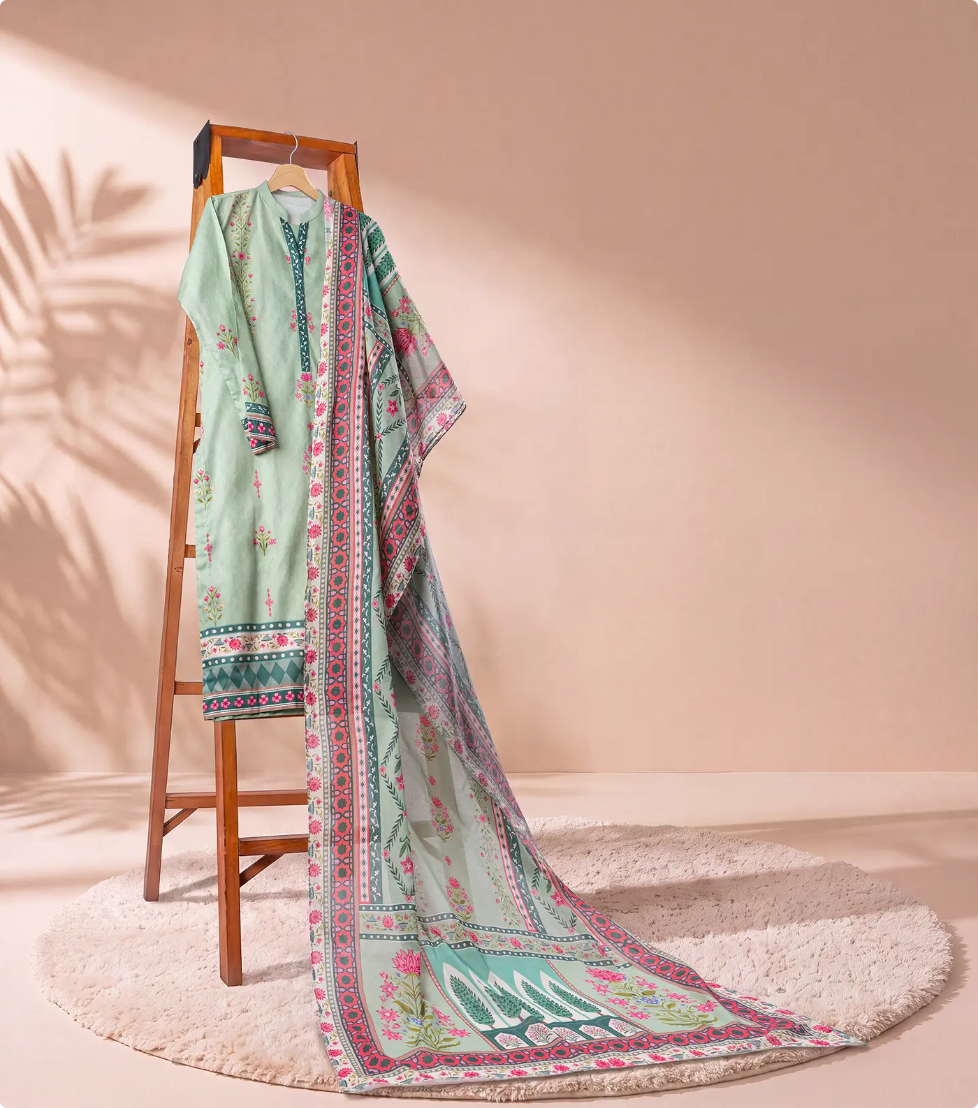 Sage green 3 piece unstitched lawn suit on a wooden ladder with trailing printed voile dupatta